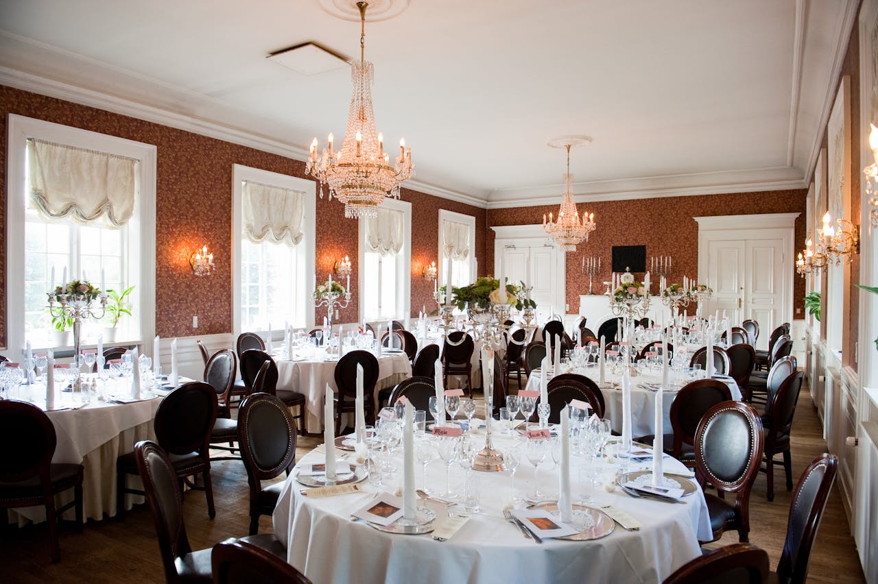 Luxurious dining room interior featuring chandeliers, elegant table settings, and classic decor.