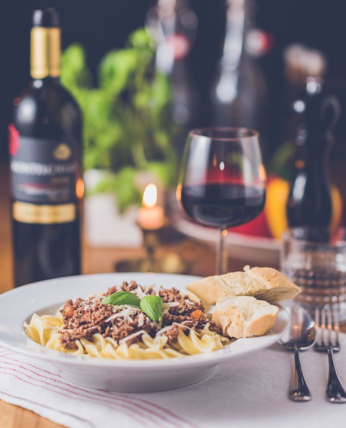 Delicious pasta meal with red wine, served in a warm restaurant setting.